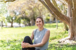 Person relaxing under a tree in a sunny park setting.