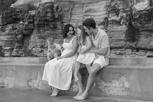 A romantic black and white photo of a couple sitting together on stone steps against a rocky wall.