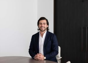 Person in navy blazer and white shirt sitting at conference table in modern office.