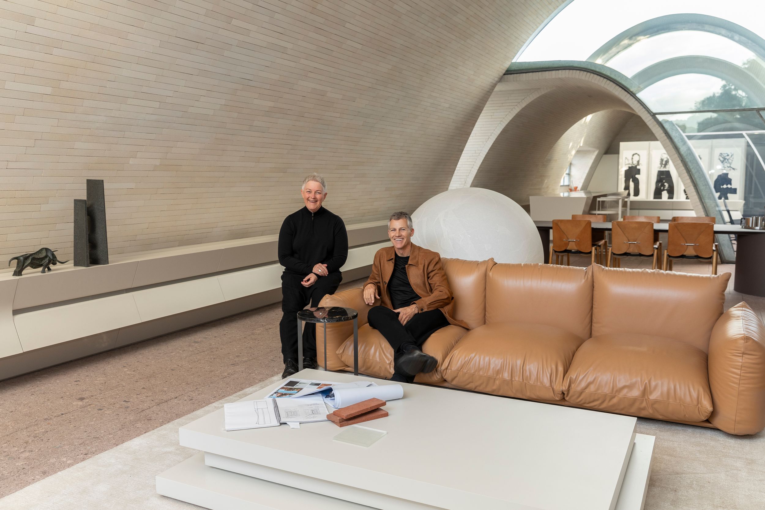 Modern curved architectural interior with leather sofa and arched ceiling design.