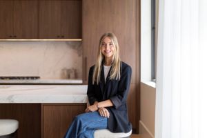 Modern minimalist kitchen interior with person sitting on barstool.