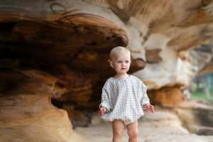 Young child in white dress exploring rocky cave formations.