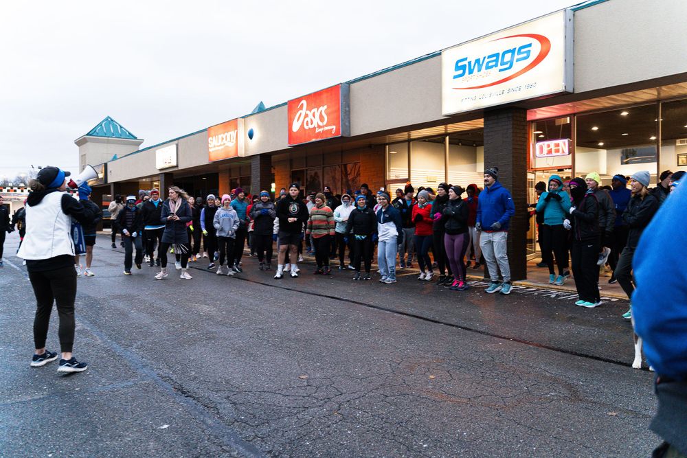 Long line of customers waiting outside shopping center storefront.