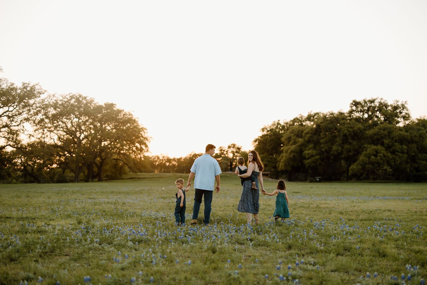 A family silhouetted against the sunset in an open field.