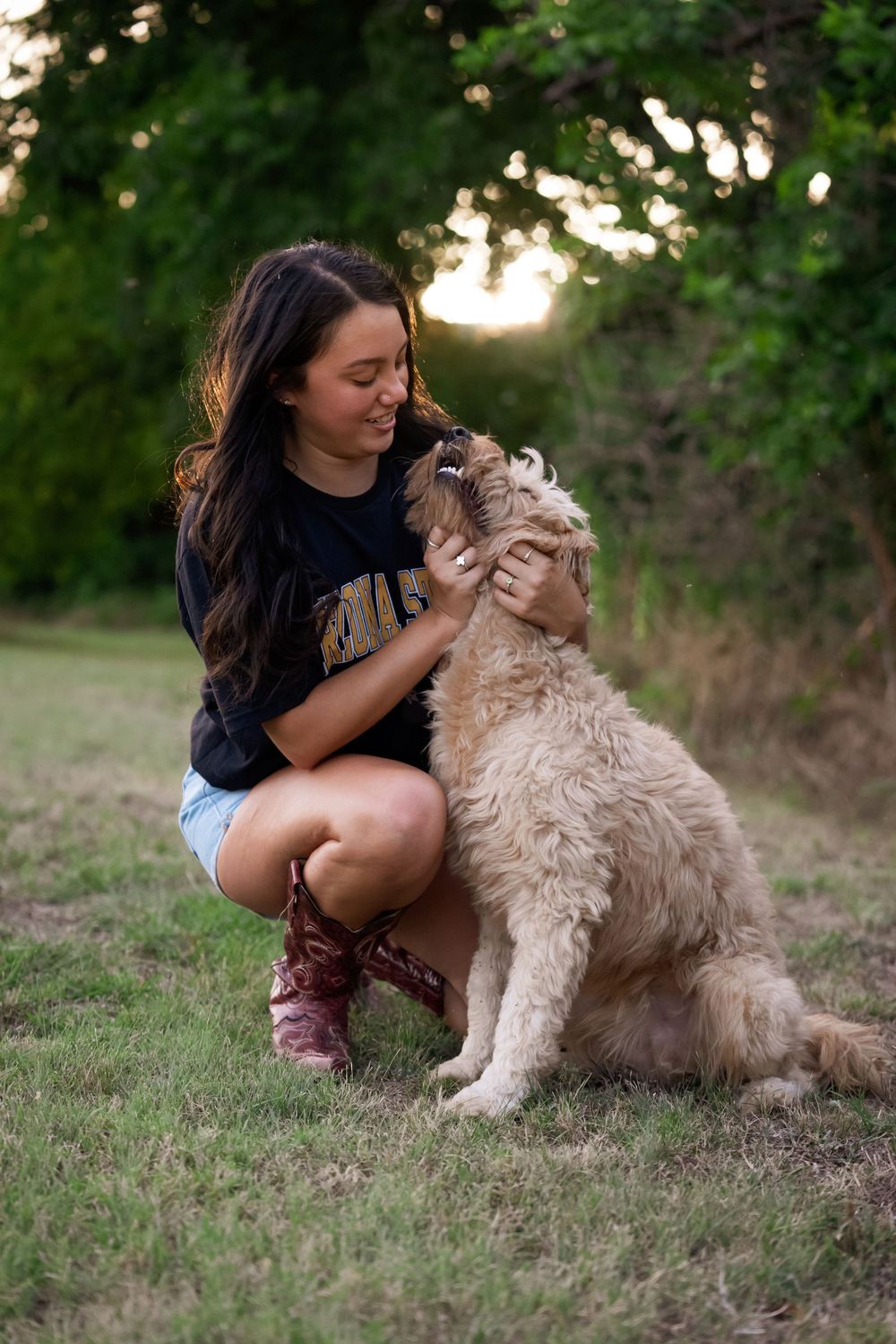 Sweet moment between a goldendoodle dog and someone wearing a college shirt in an outdoor setting.