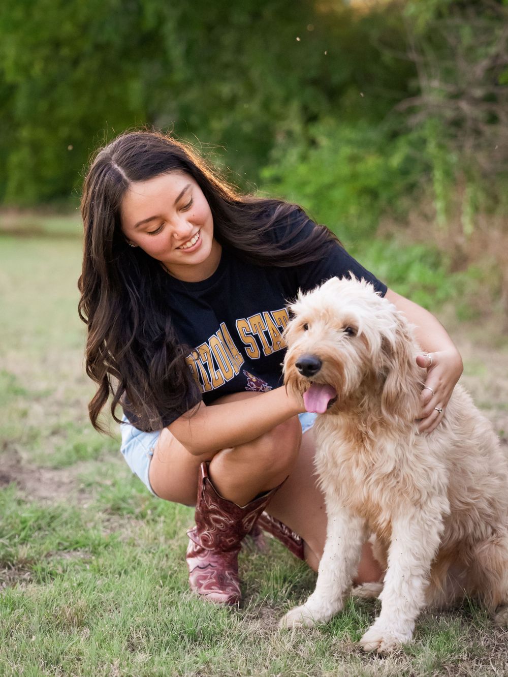 Playful moment with a happy Goldendoodle dog and its companion outdoors wearing a dark t-shirt and boots.