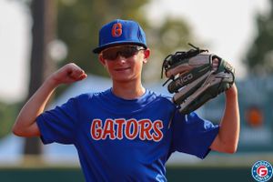 Youth baseball player in blue Gators uniform flexing while holding glove.