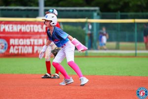 Action shot of baseball players running on red clay infield during competitive game.