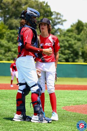 Baseball pitcher and catcher having a mound conference during a game.