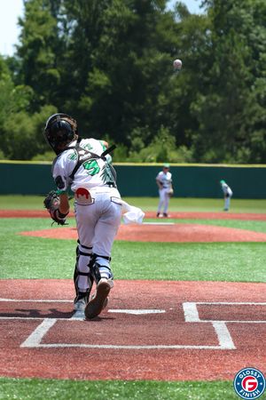 Baseball catcher reaching up to catch high pitch at home plate.