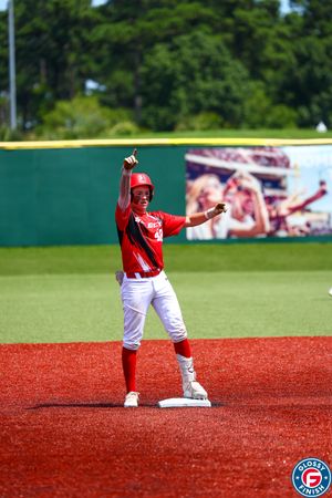 Baseball player in red uniform celebrating while standing on base.