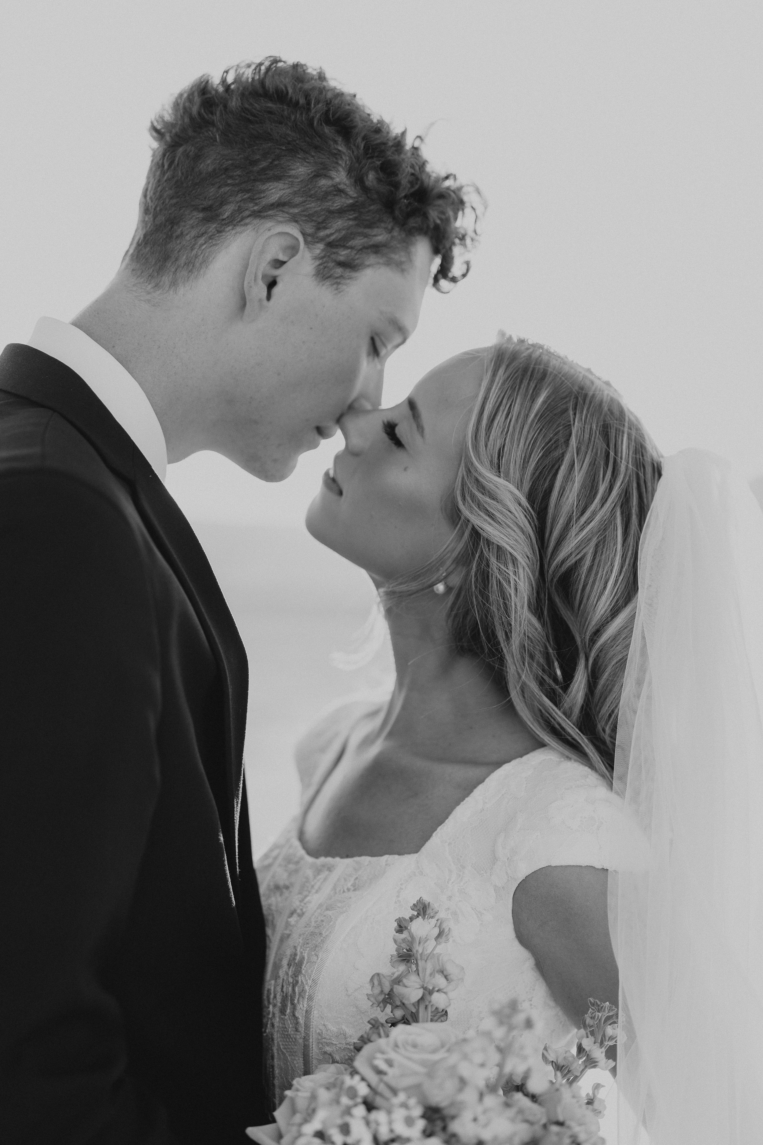 Black and white romantic wedding photo series showing intimate close-up moments between newlyweds with white flowers.