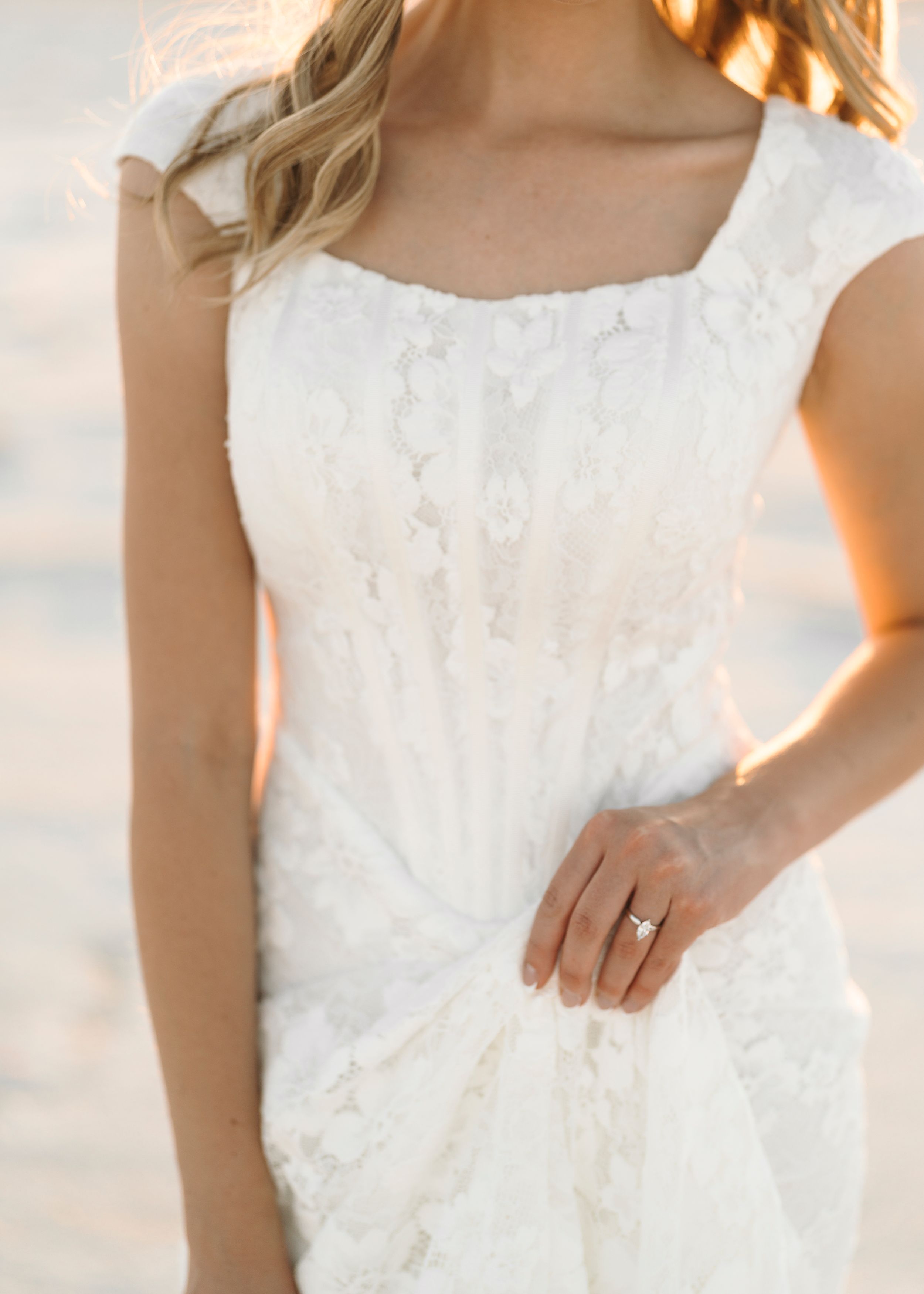 Delicate white lace detail of a wedding dress bodice shown in natural light.