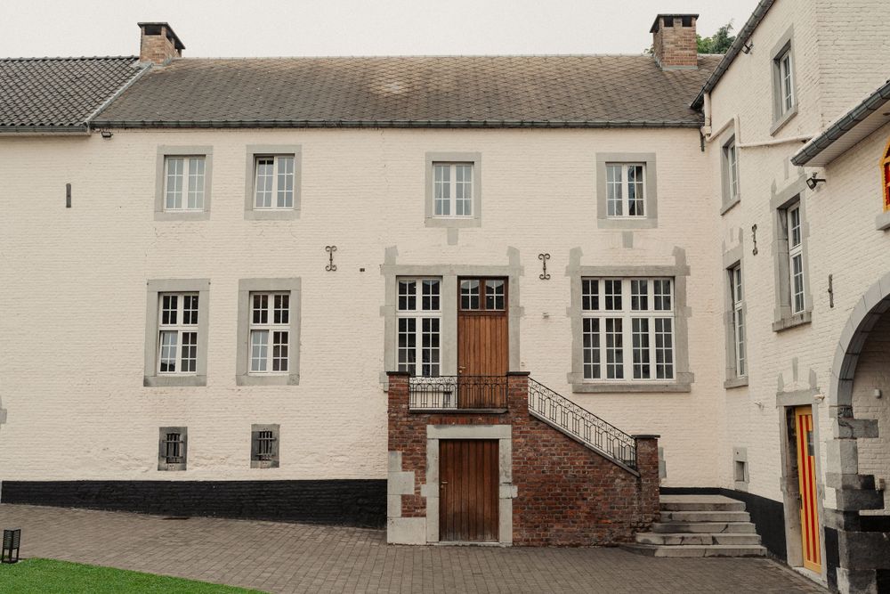 Historic white building exterior with symmetrical windows and brick staircase entrance.