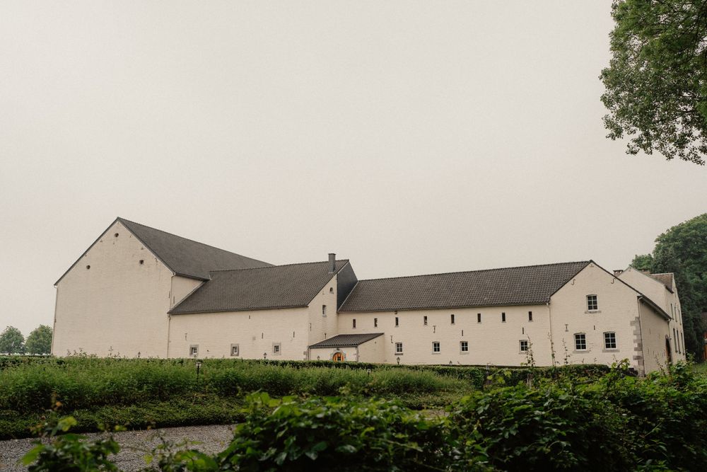 Large white farm buildings with sloped roofs surrounded by green landscape.