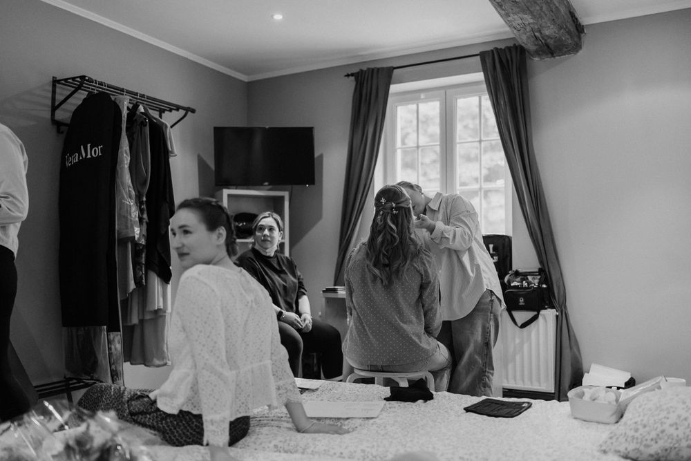 Black and white photograph of wedding preparation scene in a bright room.