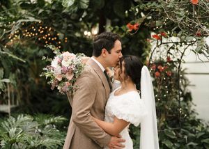 A couple shares an intimate moment under string lights at an outdoor wedding ceremony.