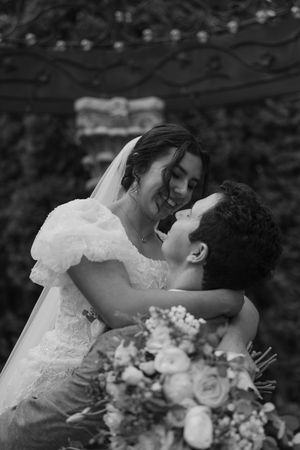 A romantic black and white photo sequence captures a tender kiss between newlyweds with a floral bouquet.