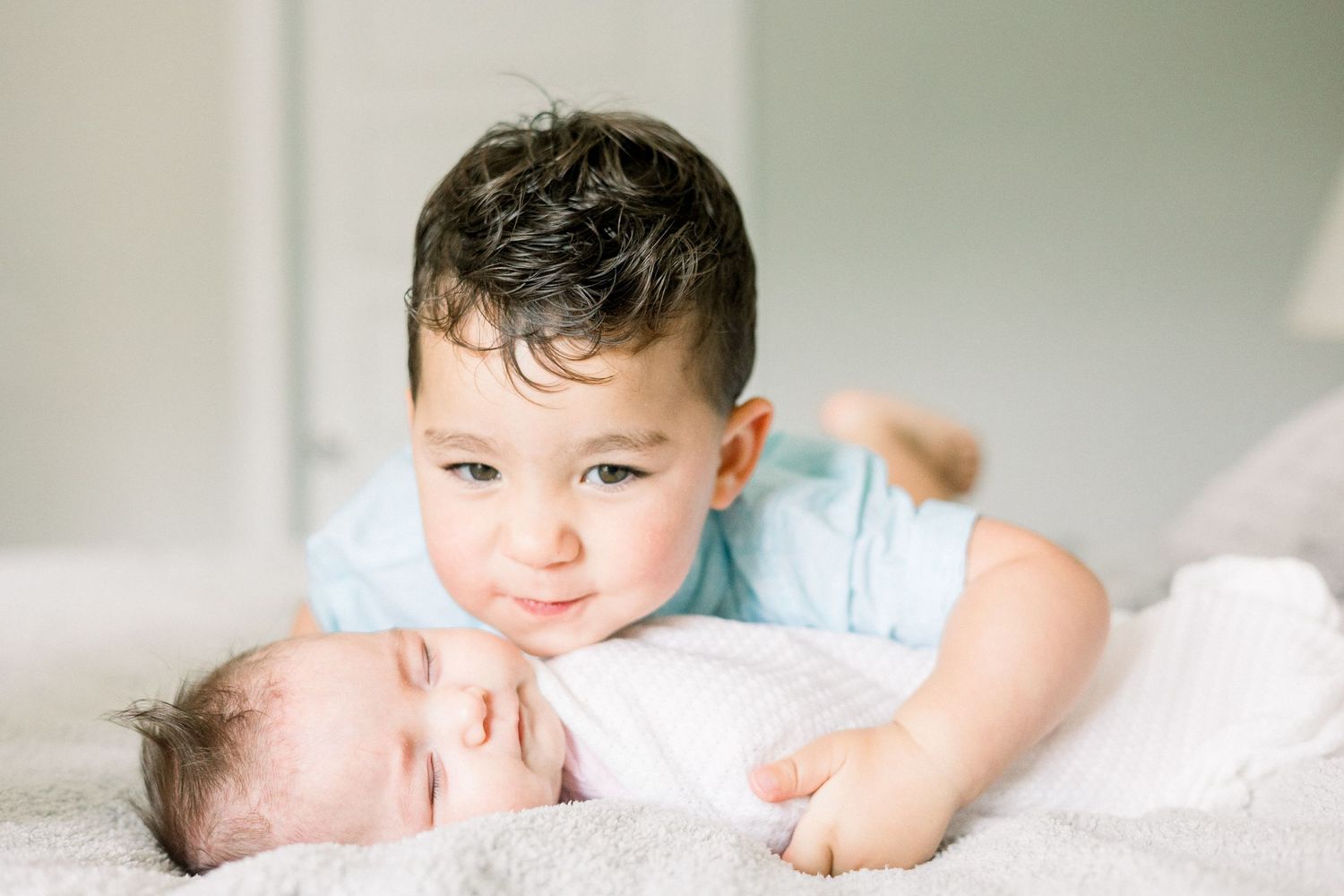 Older brother snuggling newborn sister in an Augusta, GA in-home session.