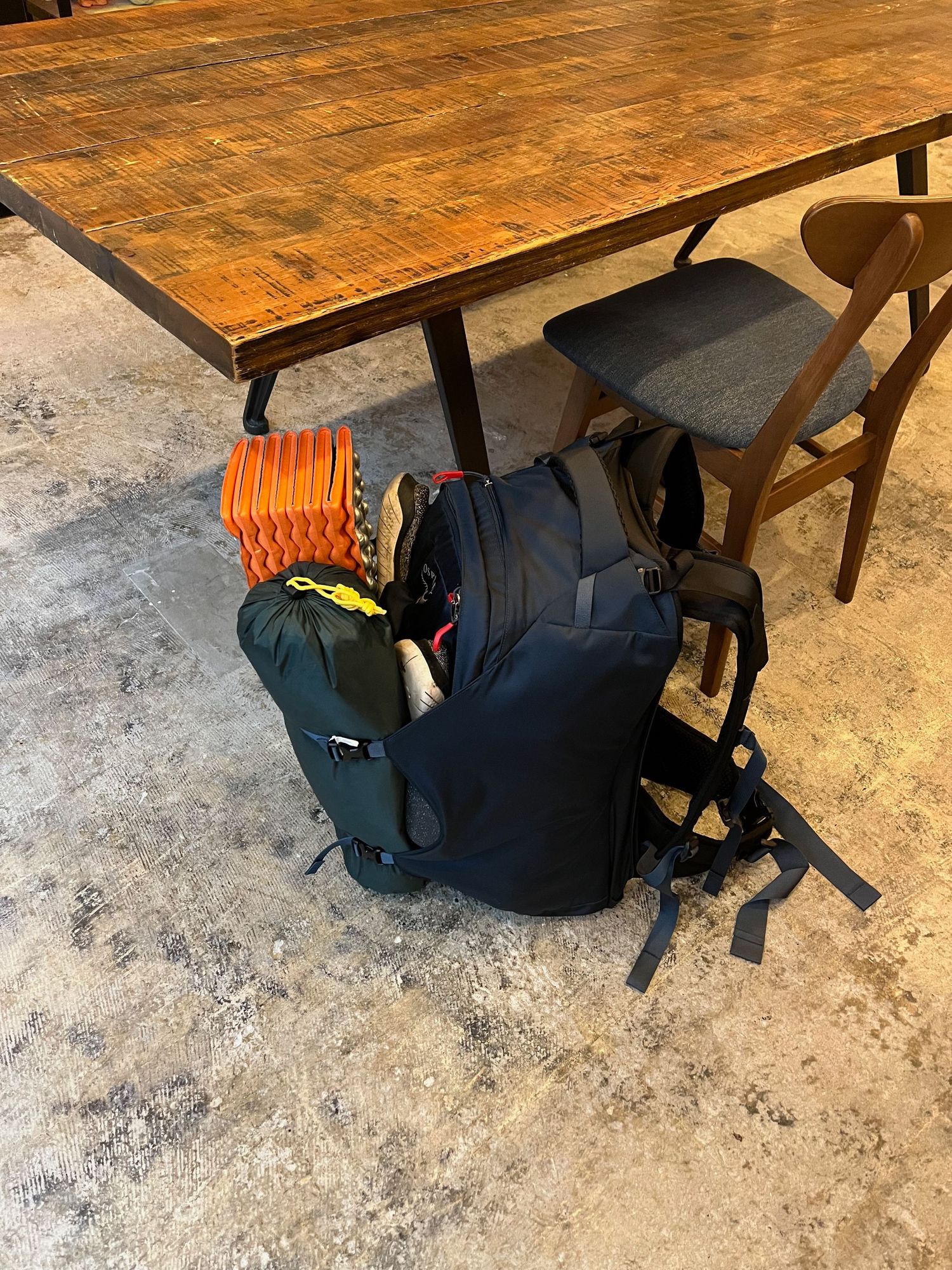 Backpacks and camping gear arranged under a rustic wooden table.