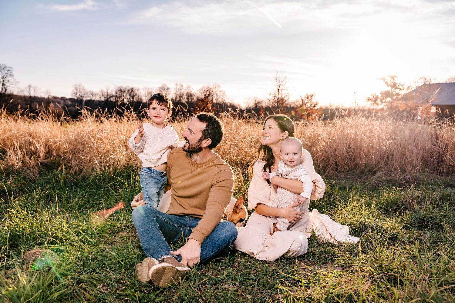 A family enjoying time together in a sunlit field of tall golden grass.