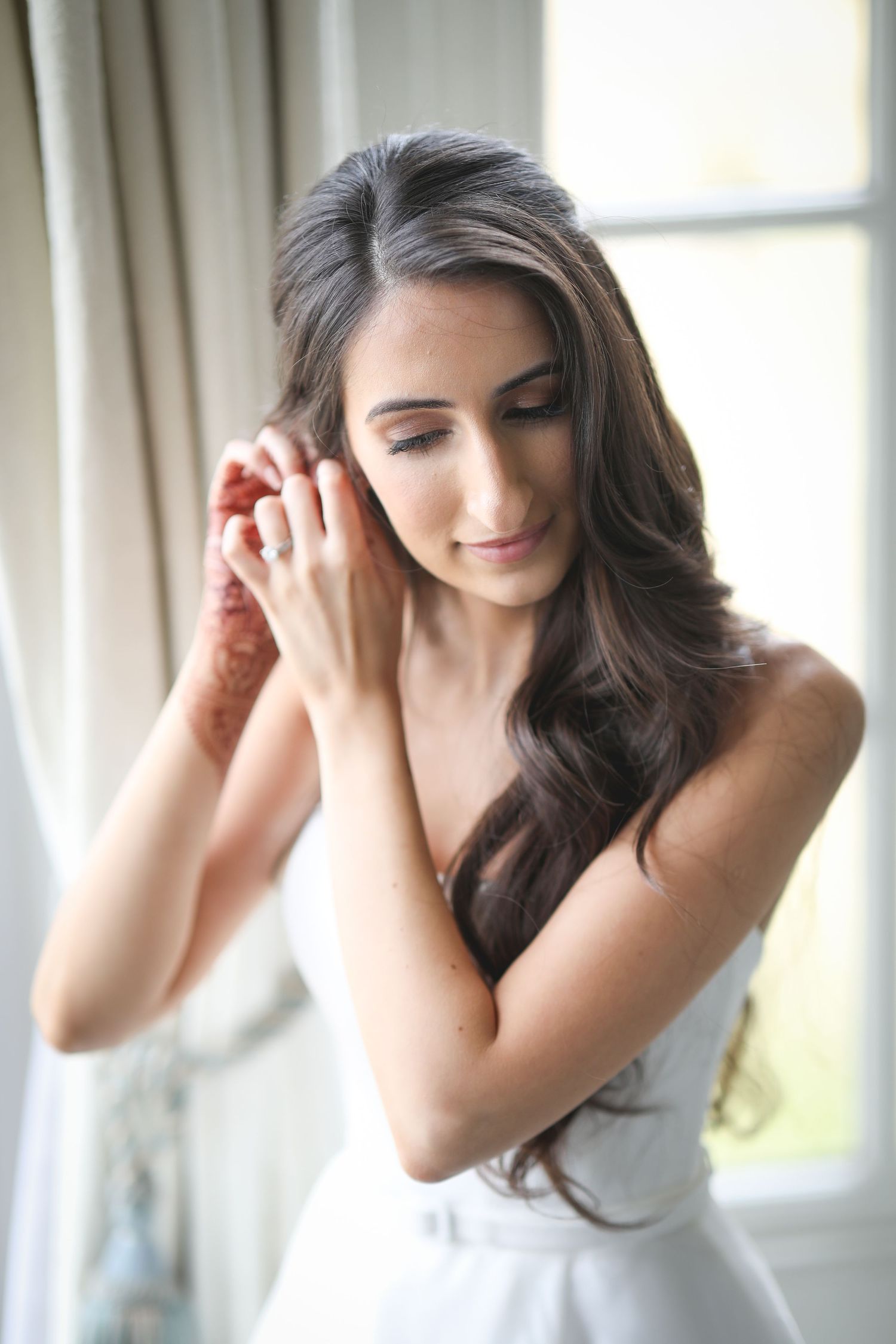 Elegant side profile portrait in natural window light shows flowing dark hair and white dress.