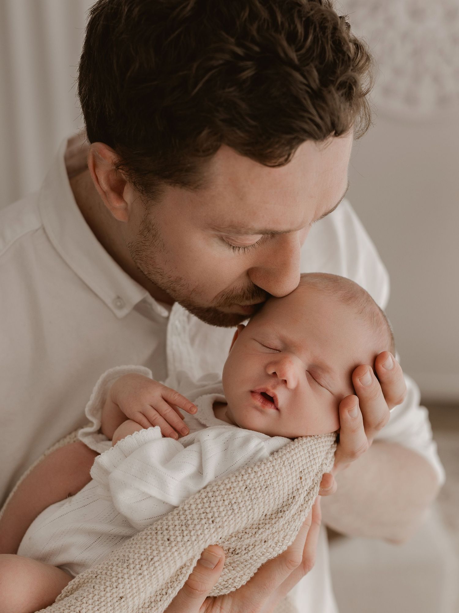 A tender moment captured in a series of photos showing a parent gently kissing a baby's cheek in soft, neutral tones.