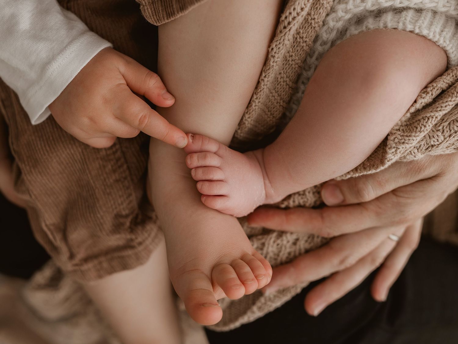 Close-up photos of baby feet in warm neutral tones showing tender parent-child moments.