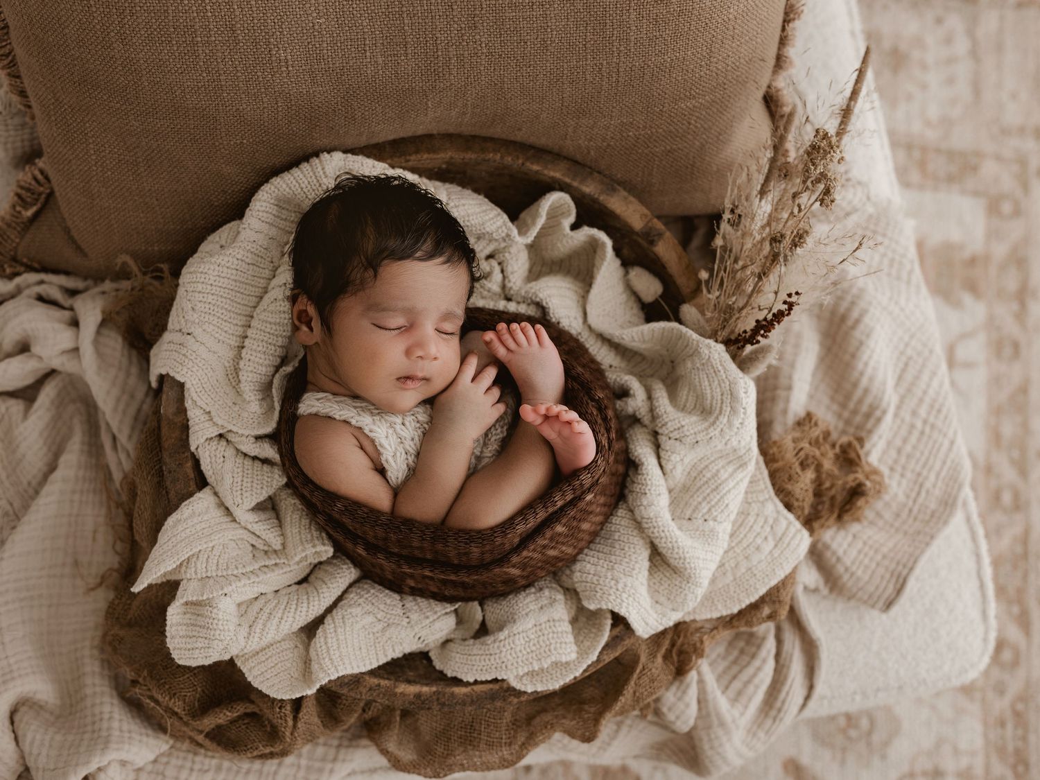 A collage of five newborn baby photos in neutral tones showing peaceful sleeping poses in baskets and blankets.