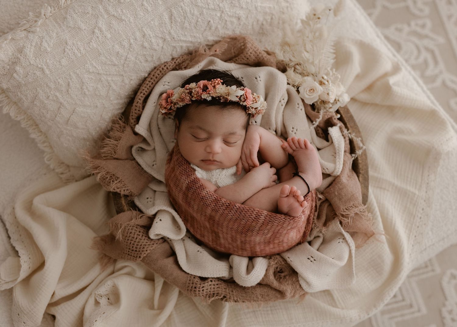 A collection of five soft, muted neutral newborn photography portraits arranged in a horizontal layout on lace fabric.