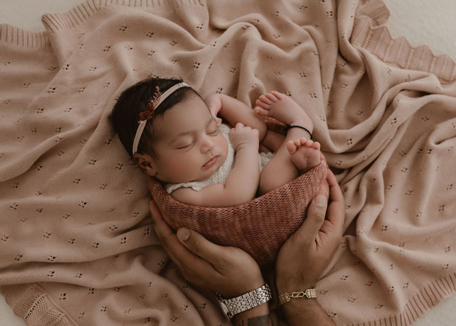 Soft beige knit blanket creates cozy backdrop for sleeping baby in neutral toned newborn photography session.