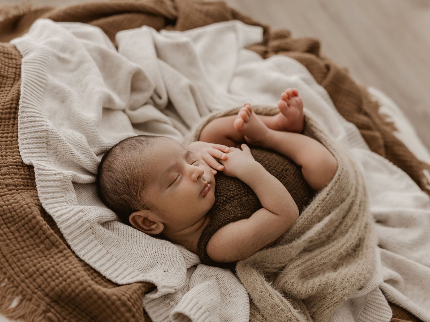 A sleeping baby lies peacefully on soft beige bedding in a series of connected photos.