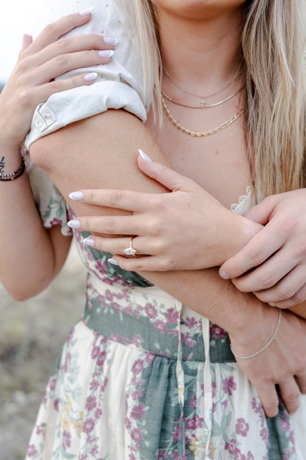 Intimate close-up of couple’s hands with engagement ring and scenic background in Texas Hill Country.