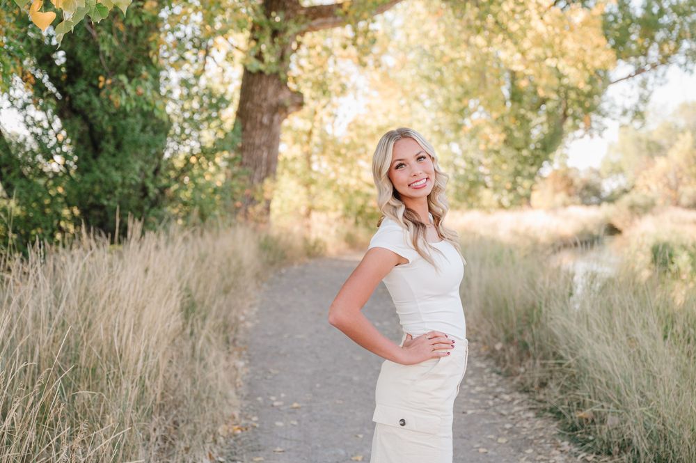 A portrait session on a nature trail with tall grasses and warm sunset lighting in the background.