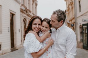 Portrait of a family of three smiling warmly in Upper Town, Zagreb, showcasing their joyful connection with the charming