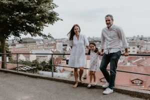 A joyful family posing together on a beautiful day in Upper Town, with historic architecture in the background.