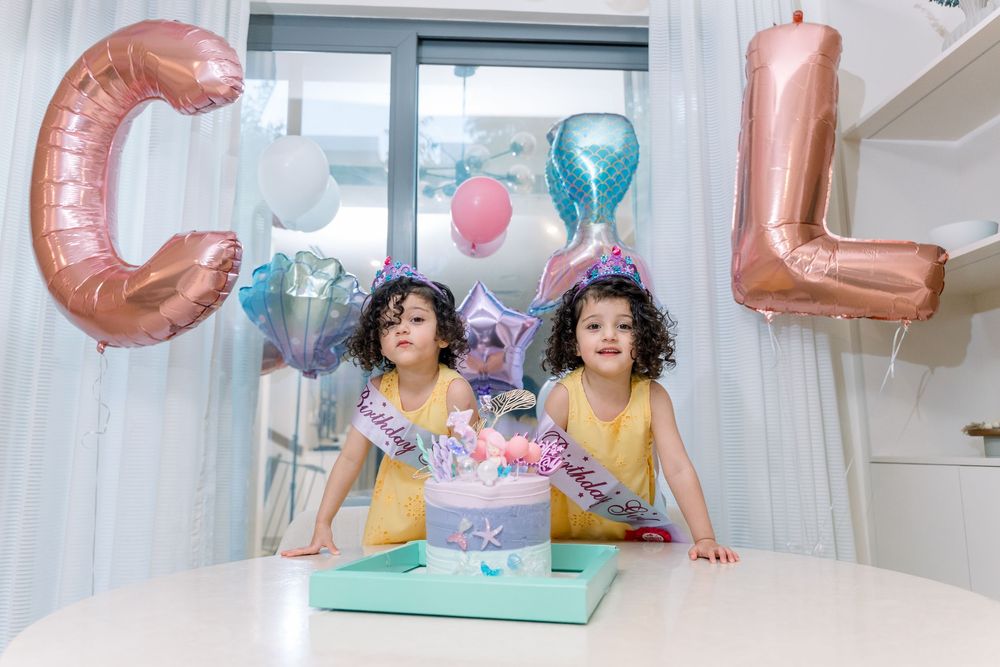 Birthday celebration setup with large balloon letters, colorful decorations and party cake on a white table.