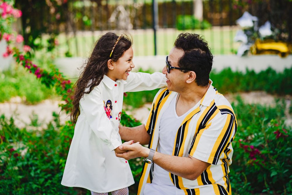 Sweet interaction between parent and child in blooming garden with pink flowers.