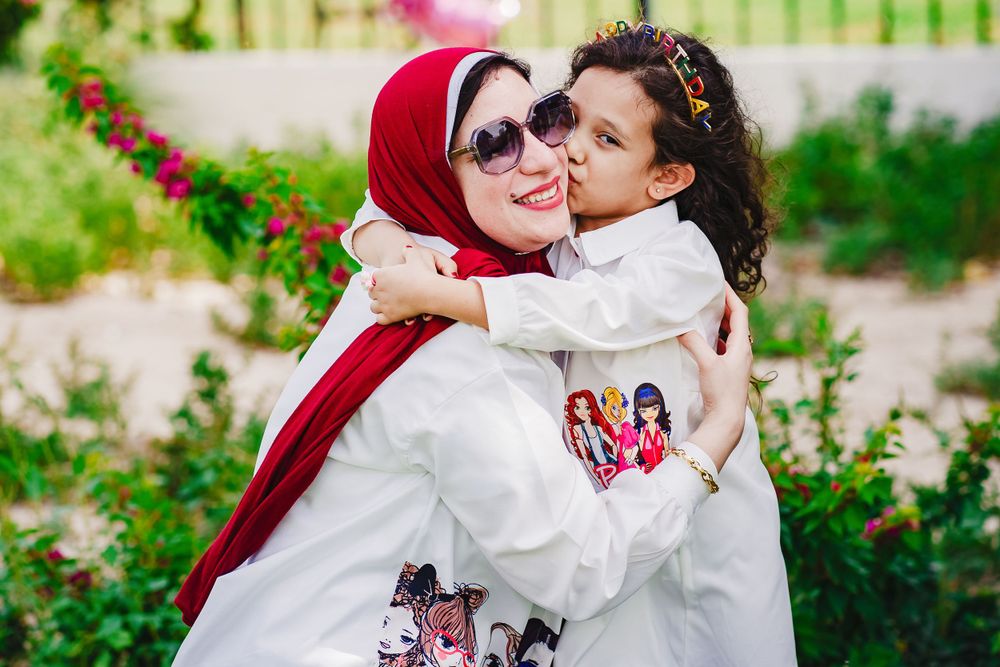 Tender moment of embrace between parent and child in garden setting.