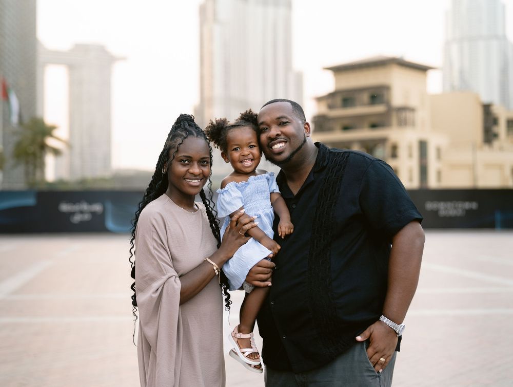 A loving family laughing and embracing while standing in an outdoor plaza at sunset.