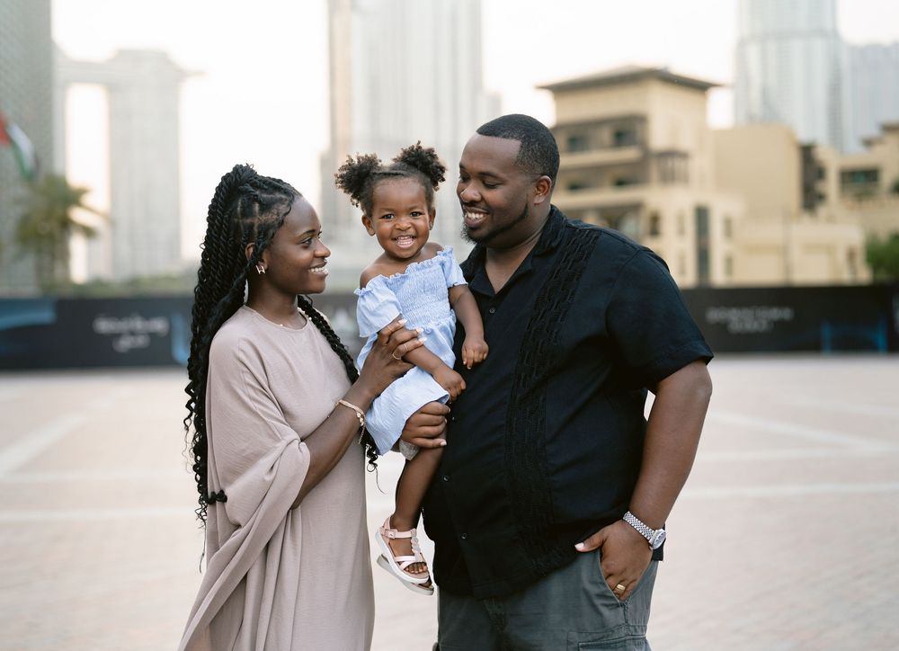 A family shares a tender moment together outdoors in an urban setting with city buildings in the background.