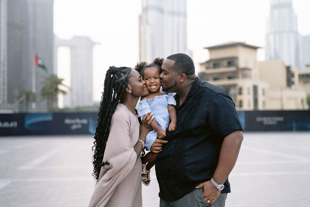 A loving family shares an intimate moment together against a cityscape backdrop in Dubai.