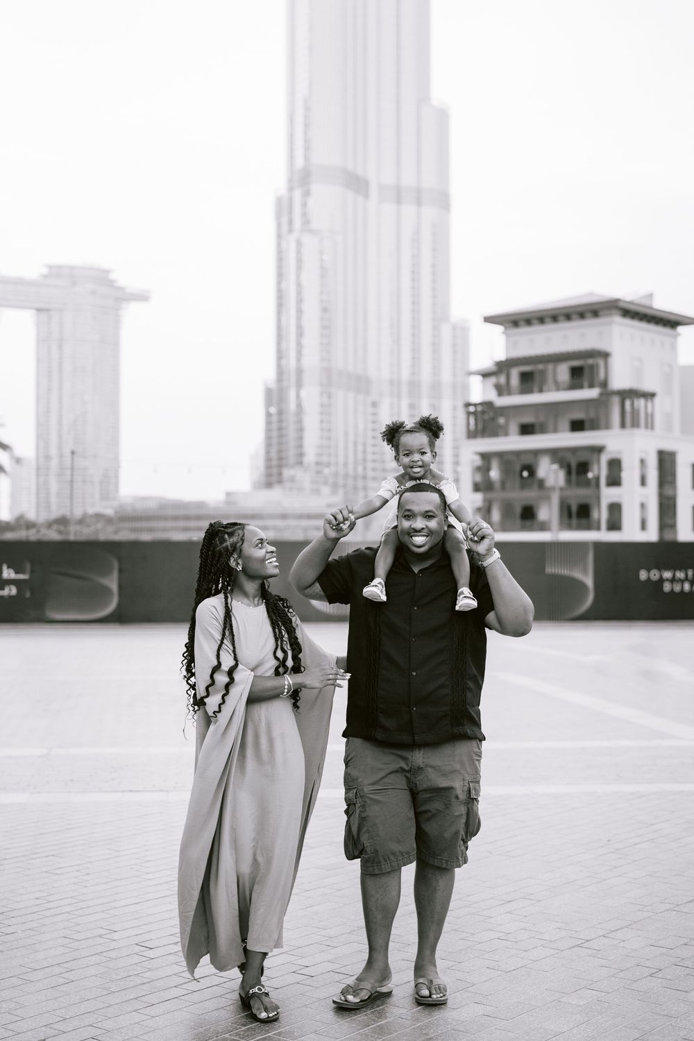 Family enjoys a day at Burj Khalifa in Dubai, with child wearing Mickey Mouse ears sitting on shoulders.