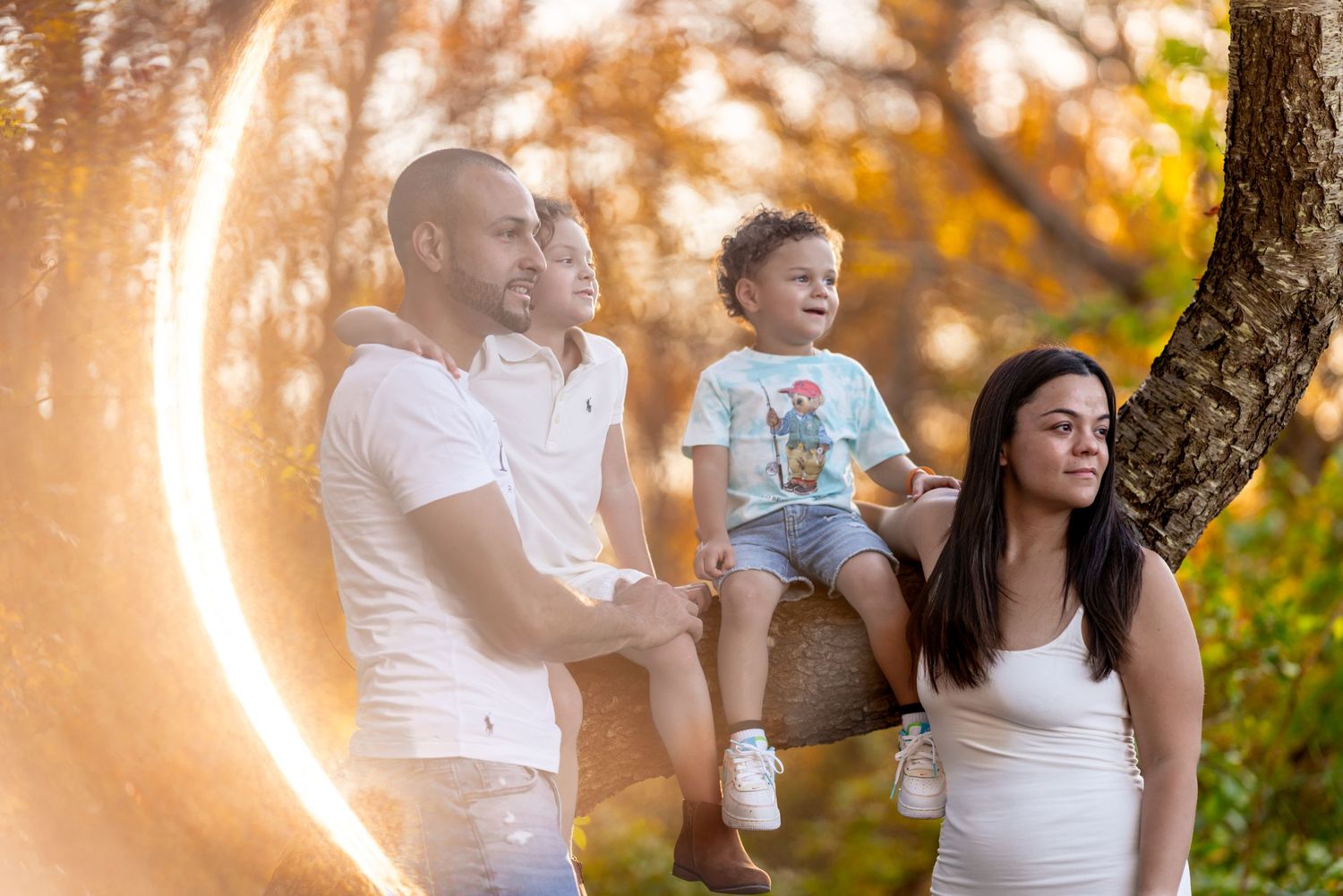 Family portrait with sunflare through trees during golden hour.
