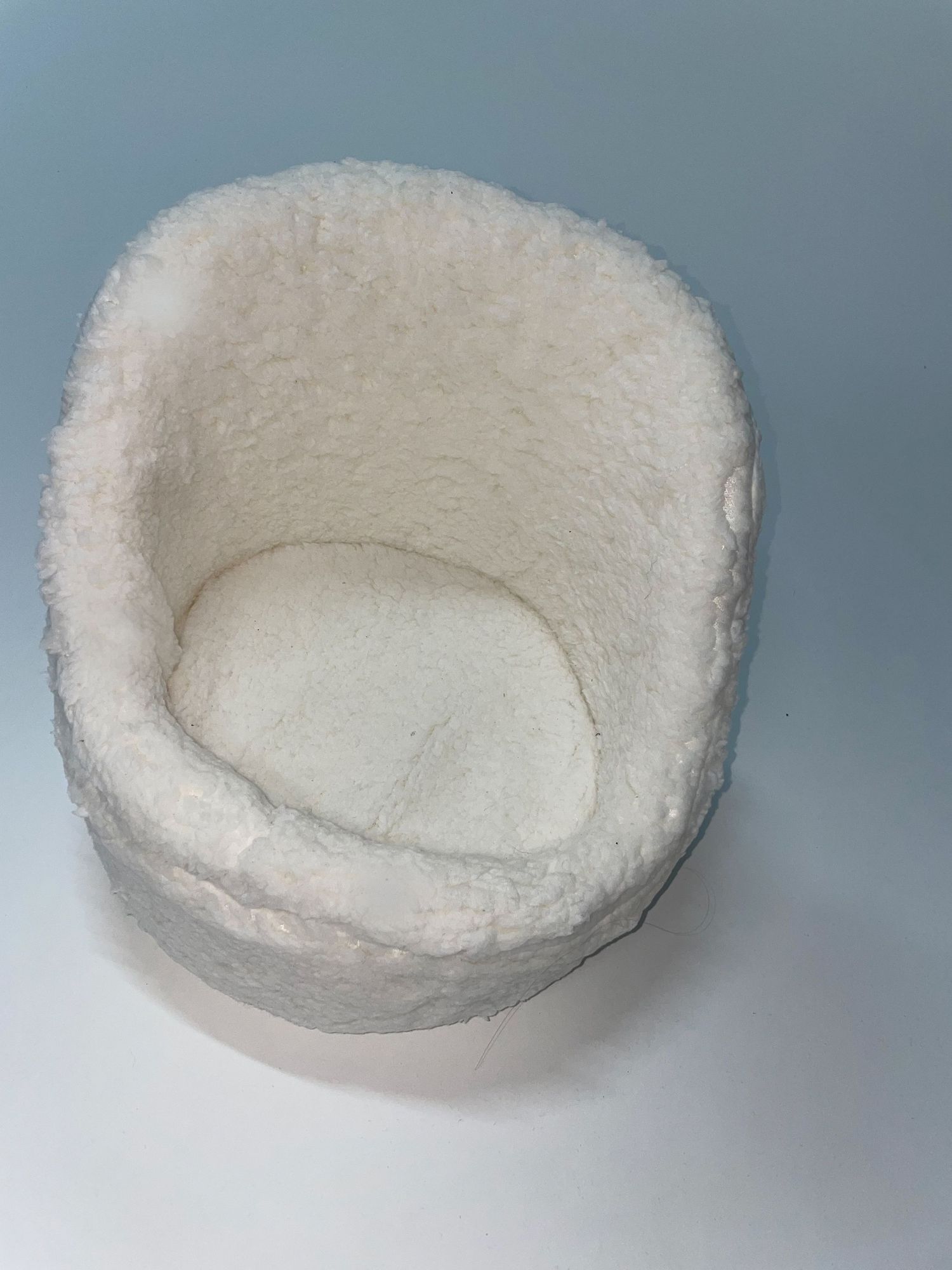 White fluffy or cotton-filled circular nest or basket shown from various angles.