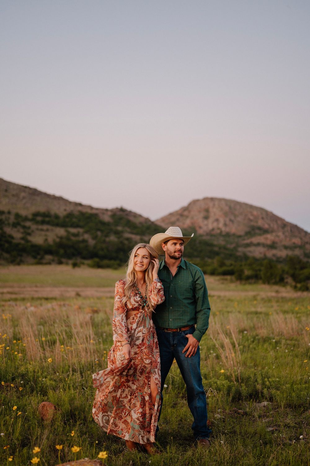 Romantic countryside photoshoot with couple in rustic attire against mountain backdrop. Oklahoma Wedding Photographer