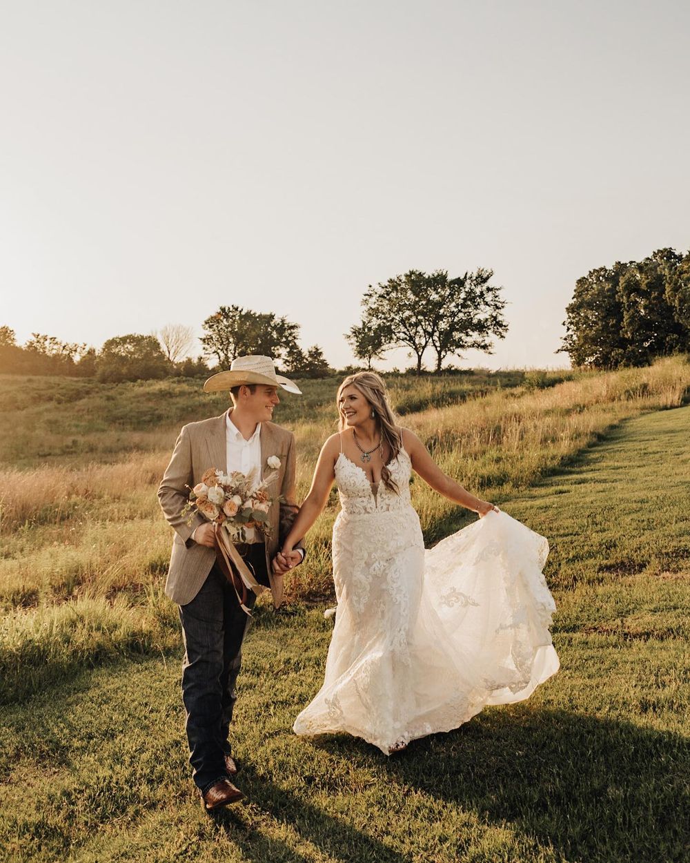 Wedding couple dances playfully in a grassy field at sunset. Oklahoma Wedding Photographer