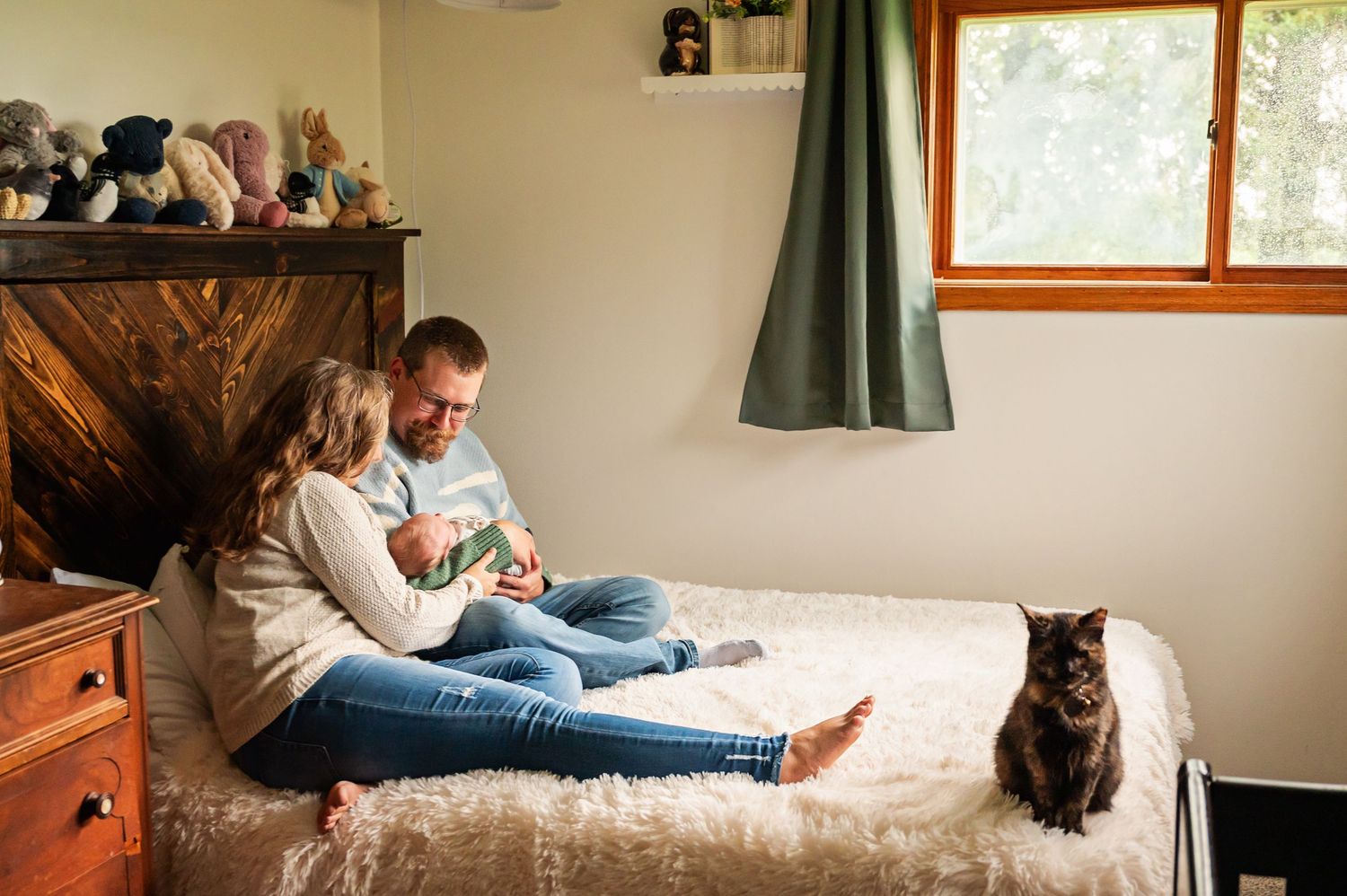 A person and cat relax together on a white bed while reading a book in a cozy bedroom.
