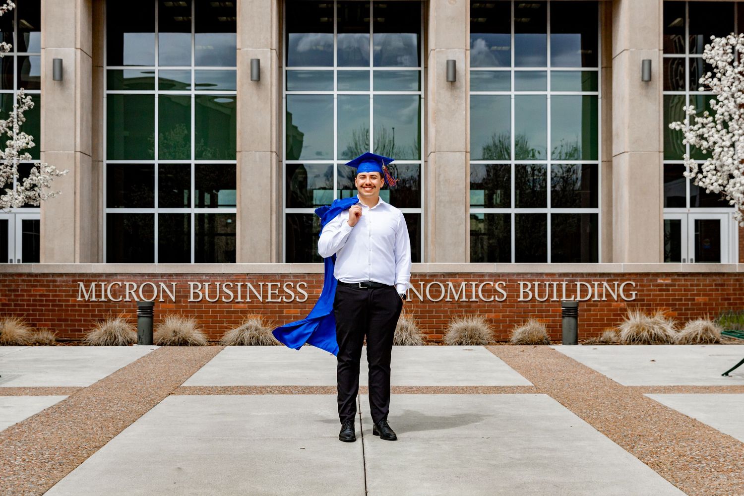 A grad posing in front of a business building