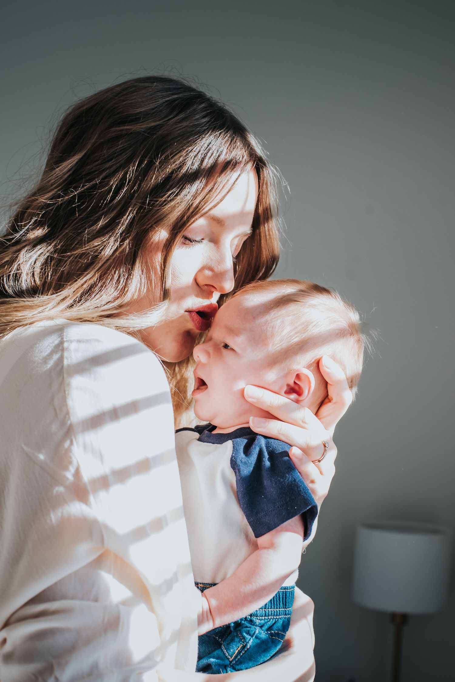 A mother holds and kisses her newborn baby boy.